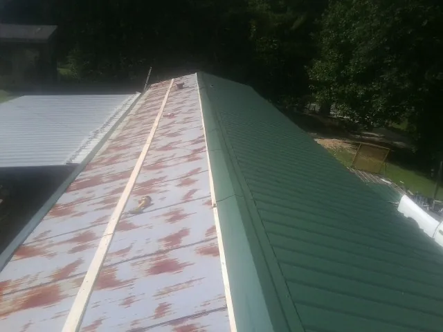 Old rusted panels beside newly installed green metal roofing — Wind Damage Roof Repair by Roofing Brothers in Kenilworth