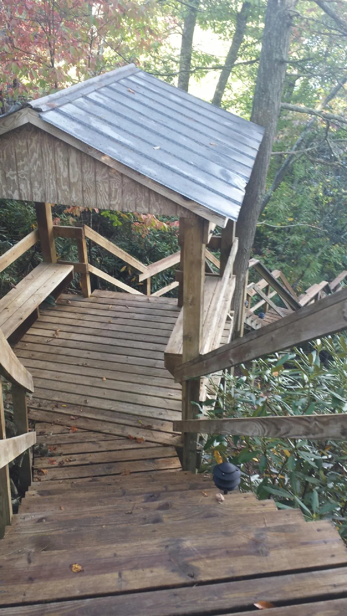 Metal roofed shelter over wooden steps on a wooded walkway — Skylight Repair & Installation work by our crew in Kenilworth